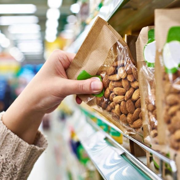 A woman picking up a big of nuts at the grocery store.