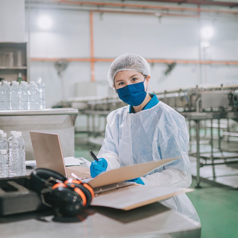 Woman wearing hair net in front of laptop in food facility